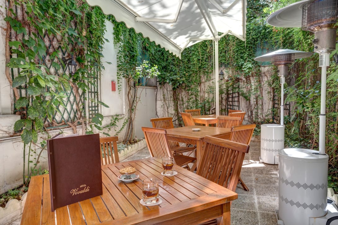 Terrasse de l'Hôtel Vivaldi avec chaises et tables en bois et décors végétal